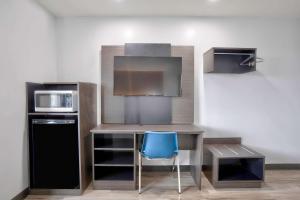 a kitchen with a desk with a microwave and a blue chair at Motel 6-Benbrook, TX - Fort Worth in Benbrook