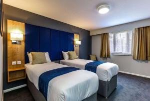 twee bedden in een hotelkamer met blauwe muren bij Days Inn Warwick Northbound M40 in Warwick