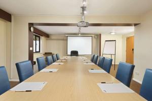Days Inn Warwick Northbound M40 في وارويك: قاعة اجتماعات مع طاولة طويلة وكراسي زرقاء