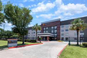 a rendering of a hotel with palm trees in front at La Quinta by Wyndham Houston NW Brookhollow in Houston