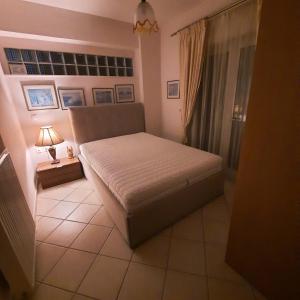 sypialnia z łóżkiem i lampką na podłodze wyłożonej kafelkami w obiekcie piu verde1 w mieście Nea Makri