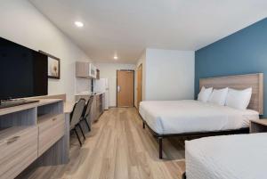 a hotel room with two beds and a flat screen tv at WoodSpring Suites Meridian in Meridian