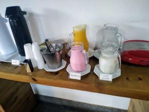 a wooden shelf with three glass jars and milk at Galeria Hotel Pousada in Jaguariúna