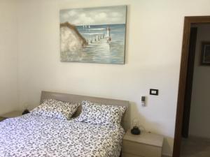 a bedroom with a bed and a painting on the wall at Appartamento a Marina di San Nicola Roma in Palo