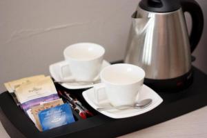 a tray with two coffee cups and a tea kettle at Hotel Browar Kościerzyna in Kościerzyna