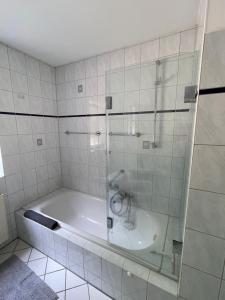 a bath tub with a glass shower in a bathroom at Strandlächeln Lodge - Ferienwohnung mit 2 Schlafzimmern in Hohenfelde