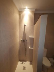 a bathroom with a toilet and a light on the wall at Apartamento con Garaje, WiFi, Centro y playa in Chipiona +11 photos