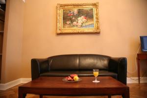 a leather couch with a table and a glass of orange juice at Hotel-Maison Am Olivaer Platz in Berlin