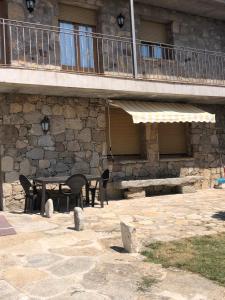 un patio con mesa y sillas frente a un edificio en Casa Rural La Curva, en Barajas de Gredos