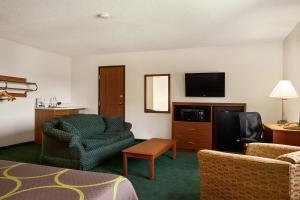 a hotel room with a couch and a chair and a television at Super 8 by Wyndham Concordia in Concordia