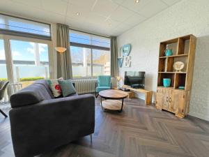 a living room with a couch and a television at Aparthotel Bos en Duin Texel in Den Hoorn