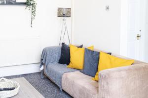 a living room with a couch with yellow pillows at RUTLAND HOUSE 10 mins from Manchester City Ctr 4-Bedroom House in Manchester