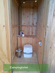 a small bathroom with a toilet in a wooden wall at Jammerbugt Glamping in Brovst