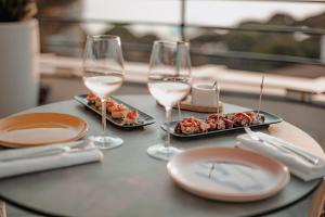 a table with two glasses of wine and plates of food at The 1932 Hotel & Spa Cap d'Antibes - MGallery Collection in Juan-les-Pins