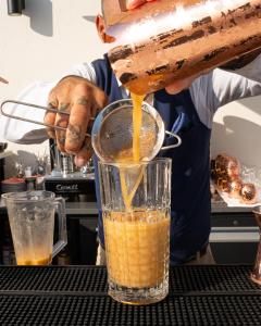 a person is pouring orange liquid into a blender at The 1932 Hotel & Spa Cap d'Antibes - MGallery Collection in Juan-les-Pins