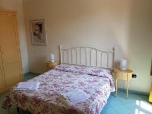 a bedroom with a bed with a floral bedspread and two tables at Villaggio Turistico Airone in Riotorto