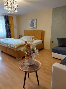 ein Schlafzimmer mit einem Bett und einem Tisch mit einer Blumenvase in der Unterkunft Hotel Olga in Austerlitz