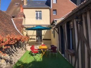 une terrasse avec une table, des chaises et un parasol dans l'établissement Les 3 p’tites pom’s, à Aleçon