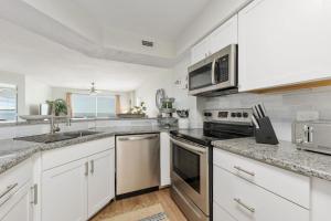 a kitchen with white cabinets and stainless steel appliances at Sea Winds 501 - Corner Breeze in Ormond Beach