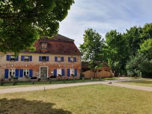 Gesindehaus am Schloss Kummerower See في Kummerow: مبنى من الطوب كبير مع مصارع زرقاء على شارع