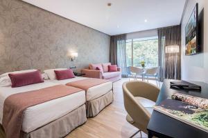 Habitación de hotel con 2 camas y escritorio en Apartosuites Jardines de Sabatini en Madrid