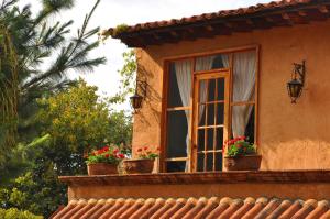a window on a house with flower pots on it at Eco Hotel Ixhi in Pátzcuaro