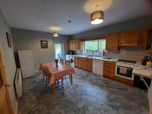 a kitchen with a table and chairs and a refrigerator at Conneelys Cottage, Connemara, Clifden, H71Y096 in Clifden