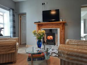 sala de estar con chimenea y TV en la parte superior en Conneelys Cottage, Connemara, Clifden, H71Y096 en Clifden