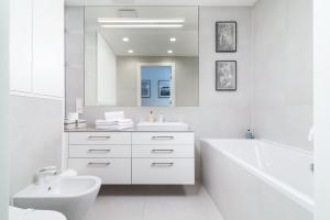 uma casa de banho branca com um lavatório, uma banheira e um WC. em Jurata Residence em Jurata