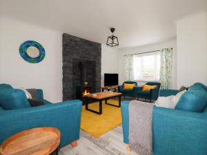 a living room with two blue couches and a fireplace at Pelagos in Bude