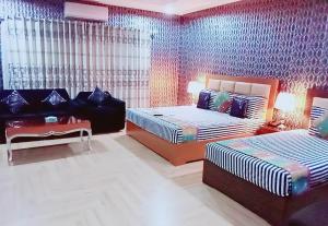 ein Schlafzimmer mit zwei Betten und einem Sofa darin in der Unterkunft Hotel Versa Appartments lodges Gulberg3 in Lahore