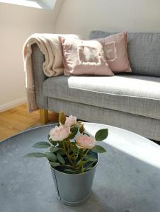 eine Vase mit rosa Blumen in einem Wohnzimmer mit Sofa in der Unterkunft Meer-Harmonie in Kiel