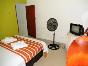 a room with a bed and a fan and a tv at Hospedaje Neydita in Iquitos
