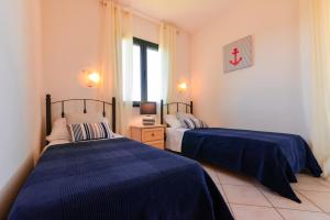 a bedroom with two beds and a window at Residence SardegnaSummer Li Cuppulati in San Teodoro