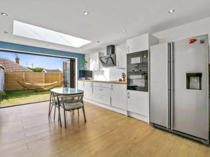 a kitchen with white appliances and a table in it at Quiet Seaside Getaway with Hot Tub, Herne Bay in Greenhill