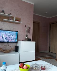 ein Wohnzimmer mit einem TV und einem Tisch mit Obst in der Unterkunft Stašenka apartment in Zlatibor