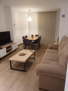 een woonkamer met een bank en een tafel met stoelen bij Apartamento Trinidad Grund in Ardales