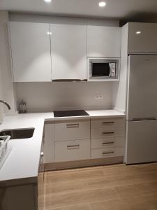 a kitchen with white cabinets and a stainless steel refrigerator at Apartamento Trinidad Grund in Ardales
