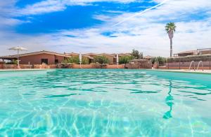 a large swimming pool with a palm tree in the background at Appartamenti Marineledda Golfo di Marinella in Golfo Aranci