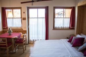 a bedroom with a bed and a table and windows at Residence Valpiccola in Val di Zoldo