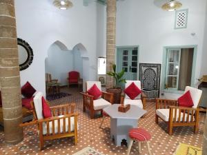 a living room with chairs and a table with red pillows at RIAD MAROSKO in Essaouira
