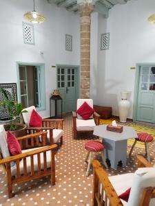 a living room with wooden chairs and a table at RIAD MAROSKO in Essaouira
