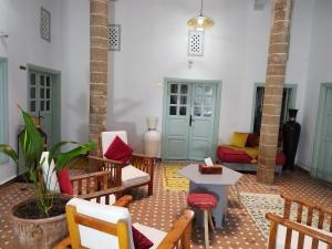 a living room with wooden chairs and a table at RIAD MAROSKO in Essaouira