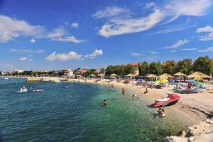 een strand met een stel mensen in het water bij Apartments by the sea Vrsi - Mulo, Zadar - 17066 in Vrsi