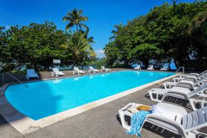 a woman laying on lounge chairs next to a swimming pool at CASTLE Hilo Hawaiian Hotel in Hilo