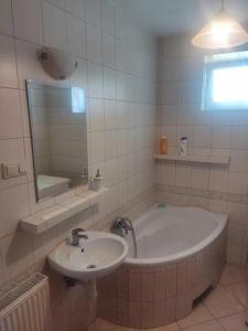 a bathroom with a tub and a sink and a mirror at Zielony Domek z dużym tajemniczym ogrodem i rekreacyjną stodołą in Obrazów