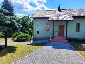 a white house with a door and a driveway at Zielony Domek z dużym tajemniczym ogrodem i rekreacyjną stodołą in Obrazów