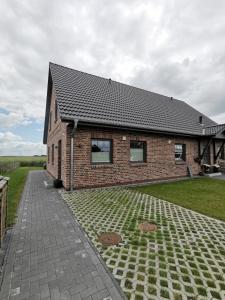 a brick house with a brick driveway in front of it at Ferienwohnung SteifeBrise in Ockholm