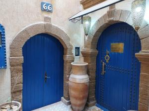 two blue doors in a building with a vase at RIAD MAROSKO in Essaouira