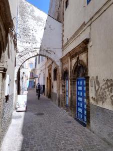 a person riding a bike down an alley way at RIAD MAROSKO in Essaouira